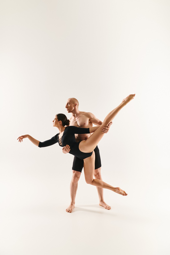 Mladý muž a žena bez košile tančí ve vzduchu, provádějí akrobatické pohyby ve studiu na bílém pozadí. - Fotografie, Obrázek