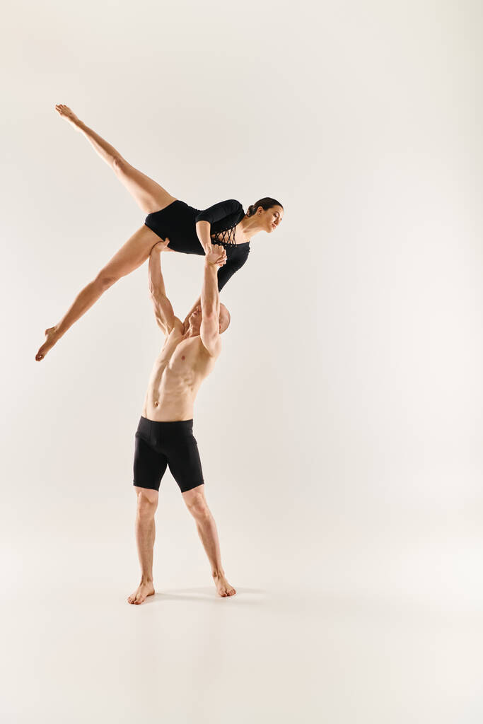 Egy félmeztelen fiatalember és egy nő egy kecses, akrobatikus táncot lejtenek a levegőben, fehér háttérrel.. - Fotó, kép