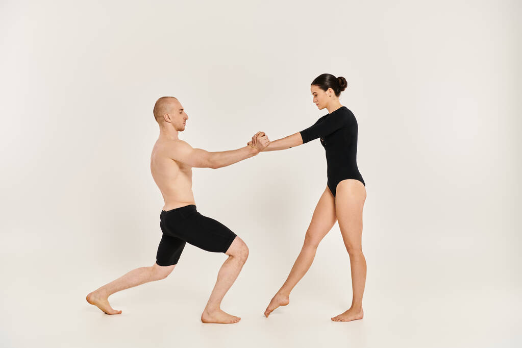Akrobatický mladý muž a žena elegantně tančí společně ve studiu, předvádějí své půvabné pohyby. - Fotografie, Obrázek
