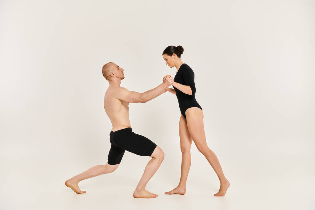 Un giovane uomo a torso nudo e una donna che si esibiscono in pose di danza intricate ed elementi acrobatici in uno studio ambientato su uno sfondo bianco. - Foto, immagini