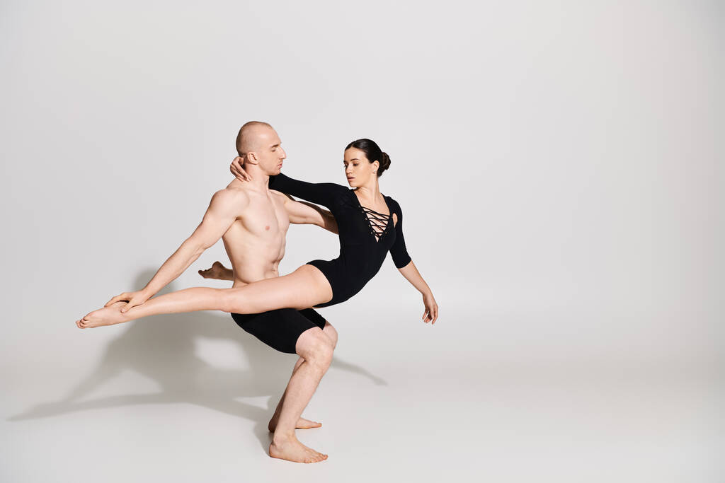 Mladý muž bez trička a žena v páru předvádějící elegantní a akrobatický tanec se pohybuje ve studiu na bílém pozadí. - Fotografie, Obrázek