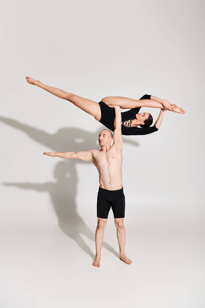 Félmeztelen fiatal férfi és nő akrobatikusan táncol egy stúdióban, fehér alapon. - Fotó, kép