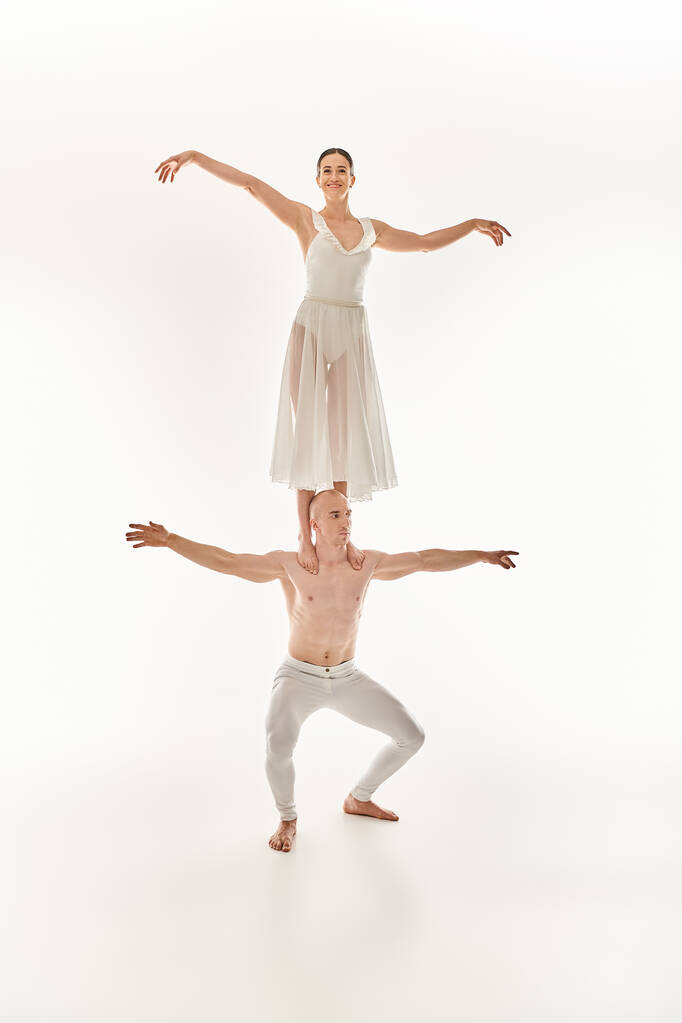 Beyaz elbiseli genç adam ve kadın zarif bir şekilde dans ediyor, akrobatik denge sergiliyor.. - Fotoğraf, Görsel