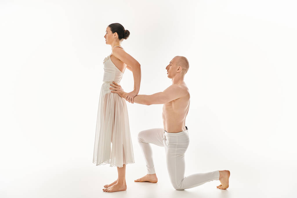 Молодий чоловік, без сорочки, і молода жінка в білій сукні виконує акробатичні елементи в витонченій танцювальній рутині. - Фото, зображення