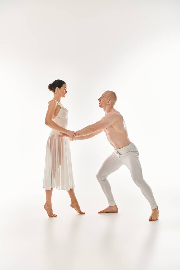 白いドレスのシャツレスの男と女性がスタジオの設定で一緒にアクロバティックダンスを行います. - 写真・画像