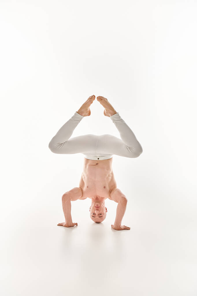 Mladý muž předvádí své akrobatické schopnosti tím, že předvede stojan na hlavu, zachycený ve studiu na bílém pozadí. - Fotografie, Obrázek