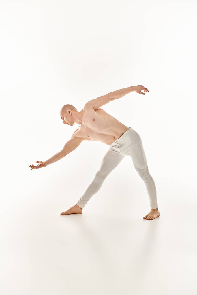 Молодой человек демонстрирует акробатические танцевальные движения с точностью и плавностью в студии на белом фоне. - Фото, изображение