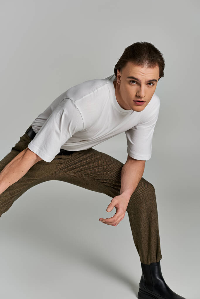appealing sophisticated man in elegant attire with brown pants posing and looking at camera - Photo, Image