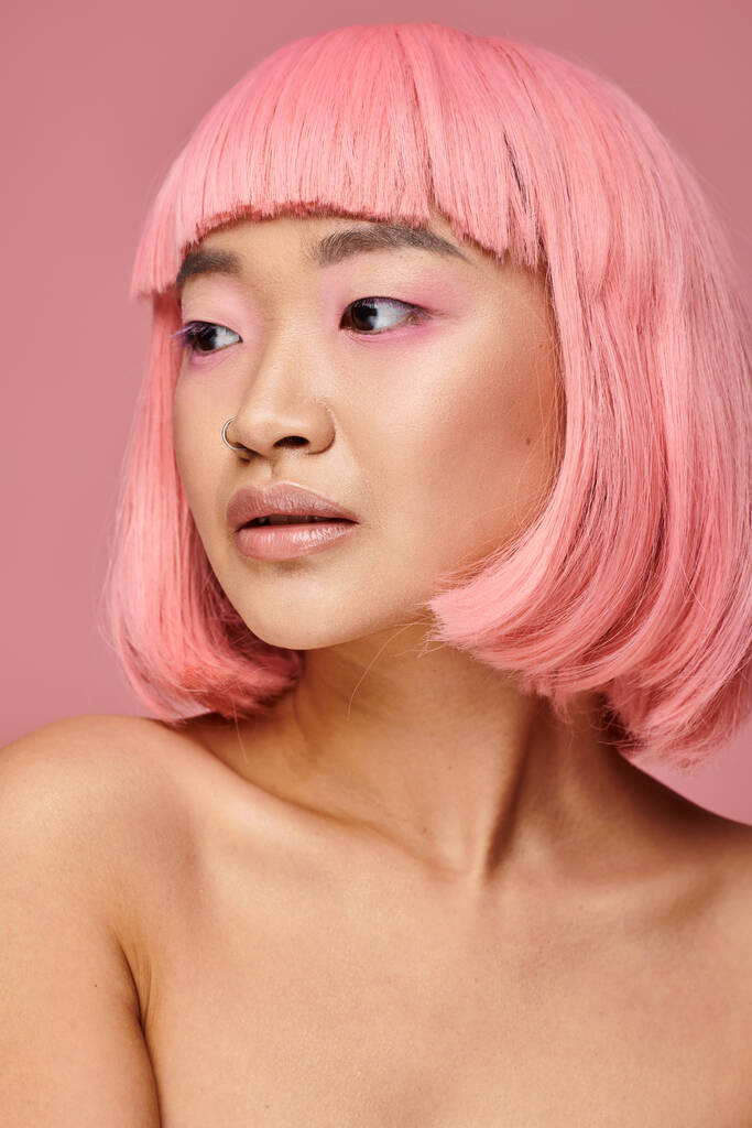 красива молода азіатська жінка з рожевим волоссям дивиться на бік яскравого фону - Фото, зображення