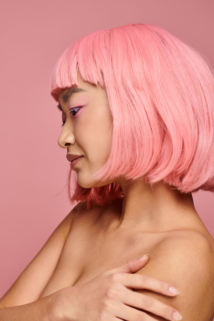 profiel van verleidelijke aziatische jonge vrouw met roze haar en make-up tegen levendige achtergrond - Foto, afbeelding