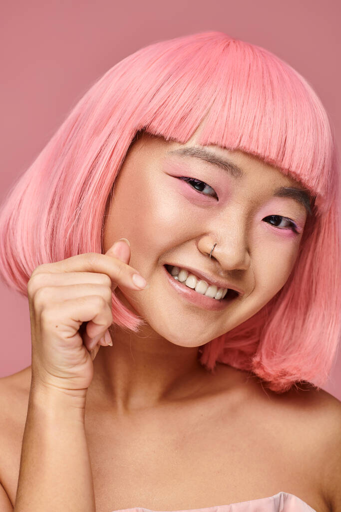 süßes asiatisches Mädchen mit Nasenpiercing, das Herzzeichen zeigt und im lebendigen Hintergrund breit lächelt - Foto, Bild
