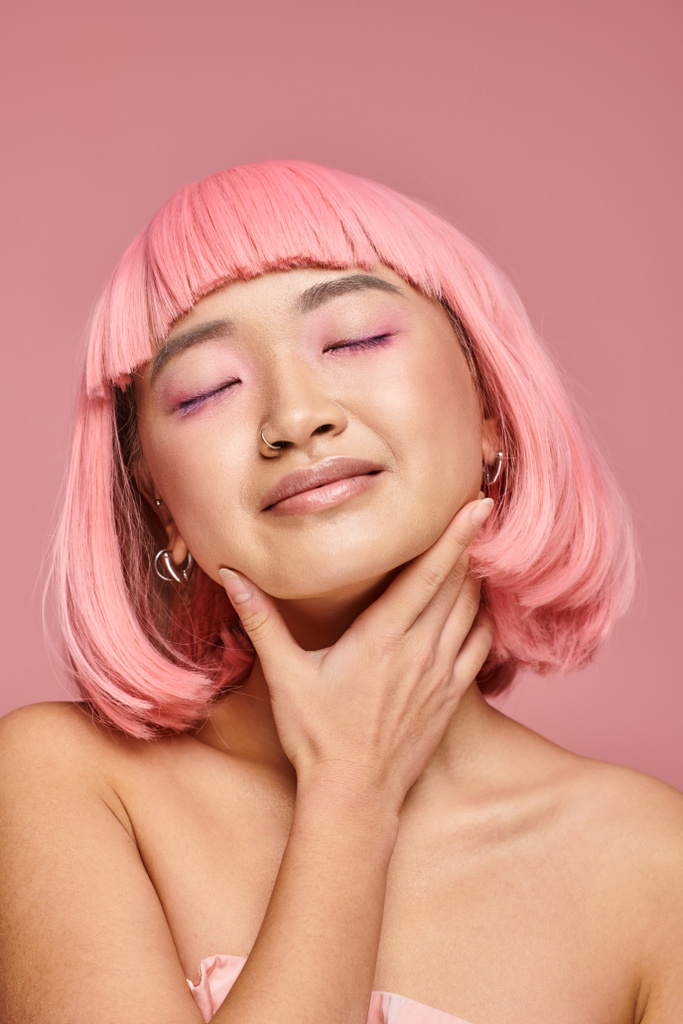 приваблива жінка з рожевим волоссям торкається підборіддя з закритими очима на яскравому фоні - Фото, зображення
