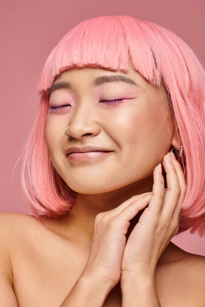 jovem atraente com cabelo rosa e maquiagem fechando os olhos e sorrindo no fundo vibrante - Foto, Imagem
