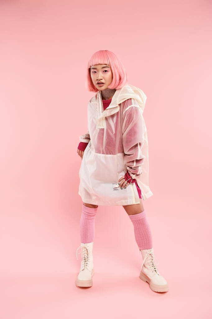 sebevědomý asijské žena v ji 20s s s růžový vlasy ve stylové oblečení pózovat na pulzující pozadí - Fotografie, Obrázek