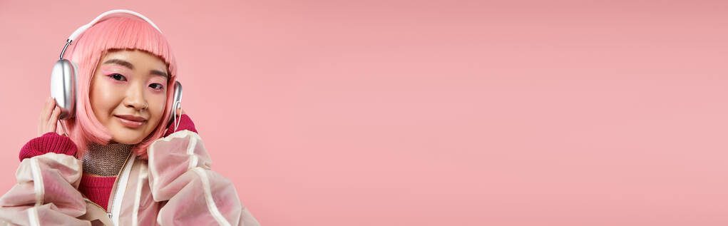 poziome ujęcie azjatki kobieta z różowymi włosami pozowanie ze słuchawkami na żywe tło - Zdjęcie, obraz