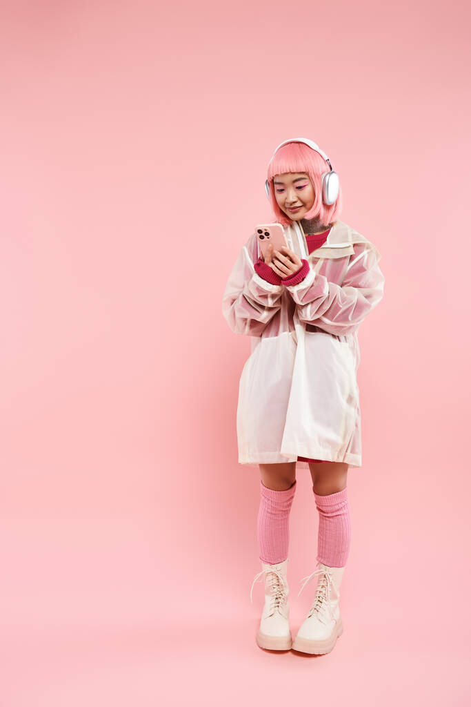 vonzó ázsiai nő rózsaszín haj fülhallgató szöveges okostelefon élénk háttér - Fotó, kép