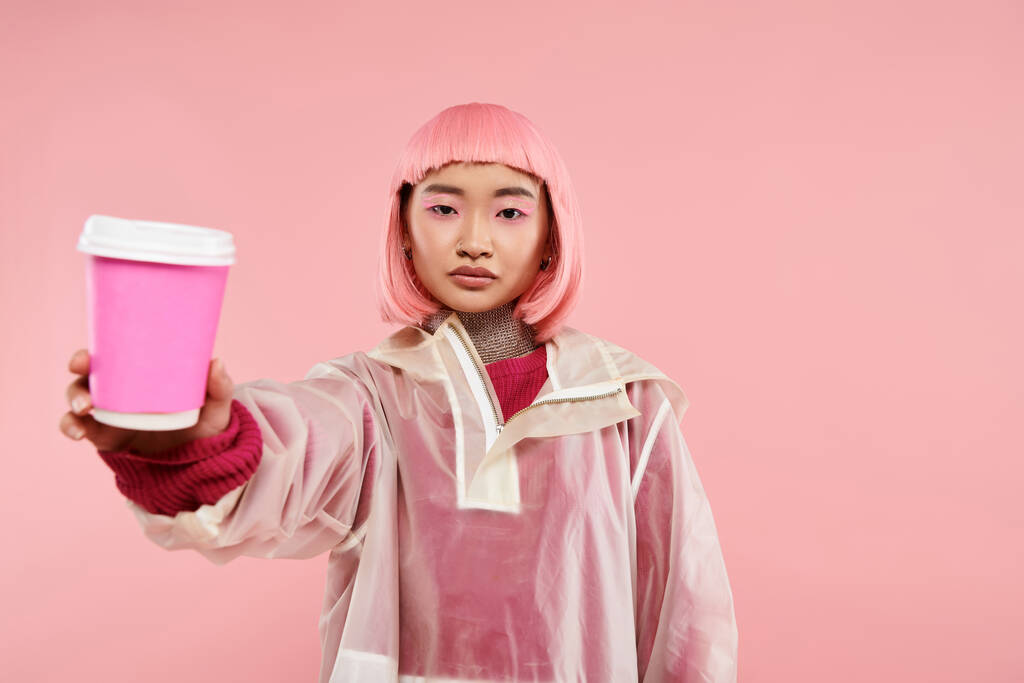 piękna azjatycka kobieta z różowymi włosami trzymając filiżankę kawy na tętniącym życiem tle - Zdjęcie, obraz