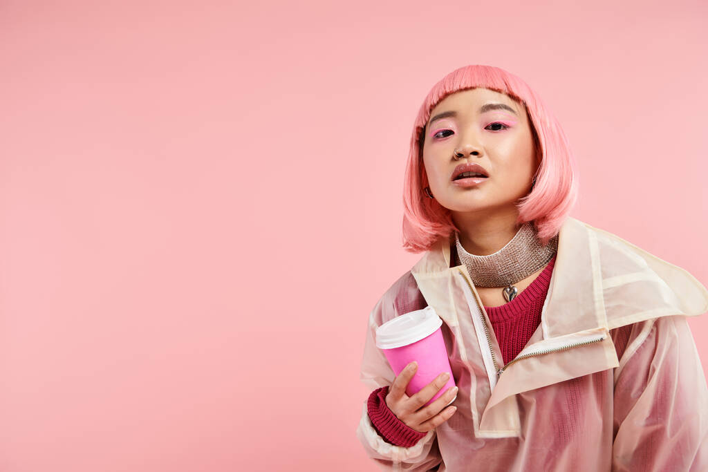 aantrekkelijk aziatisch meisje in haar twintiger jaren met roze haar poseren met kopje koffie op levendige achtergrond - Foto, afbeelding