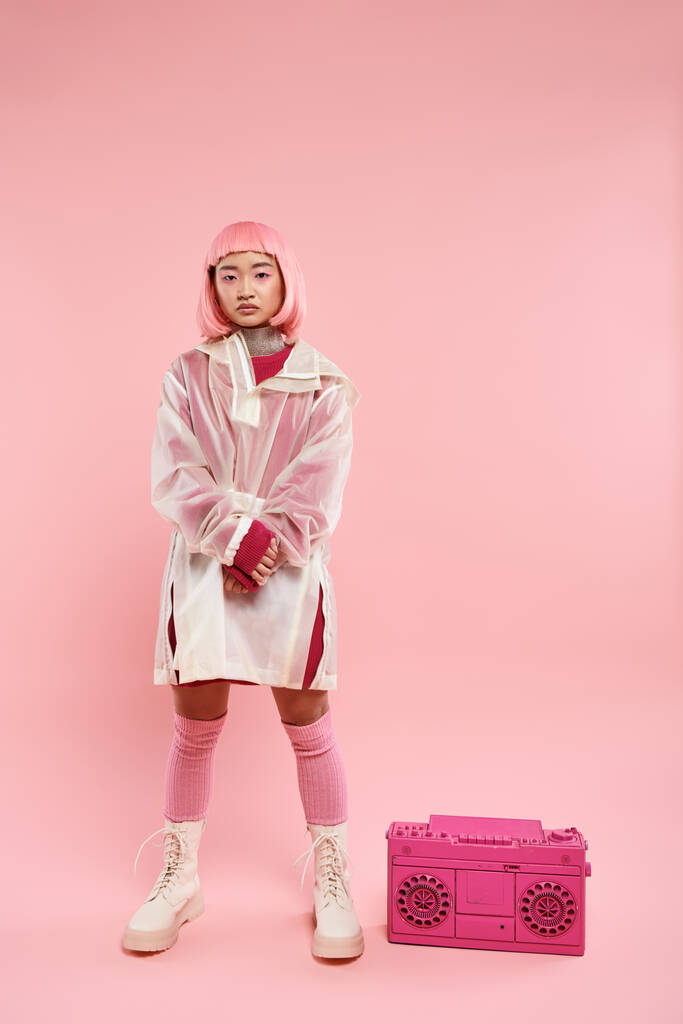 magabiztos ázsiai fiatal nő rózsaszín haj pózol boombox élénk háttér - Fotó, kép