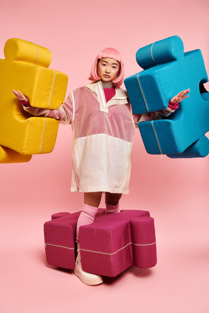 atractiva joven con el pelo rosa posando con grandes puzzles sobre un fondo vibrante - Foto, imagen