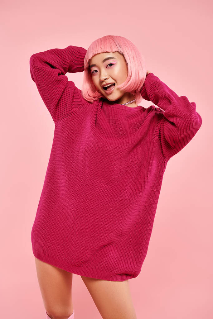 χαριτωμένο ασιατική νεαρή γυναίκα με ροζ μαλλιά και μακιγιάζ σε μεγάλο πουλόβερ σε ζωντανή φόντο - Φωτογραφία, εικόνα