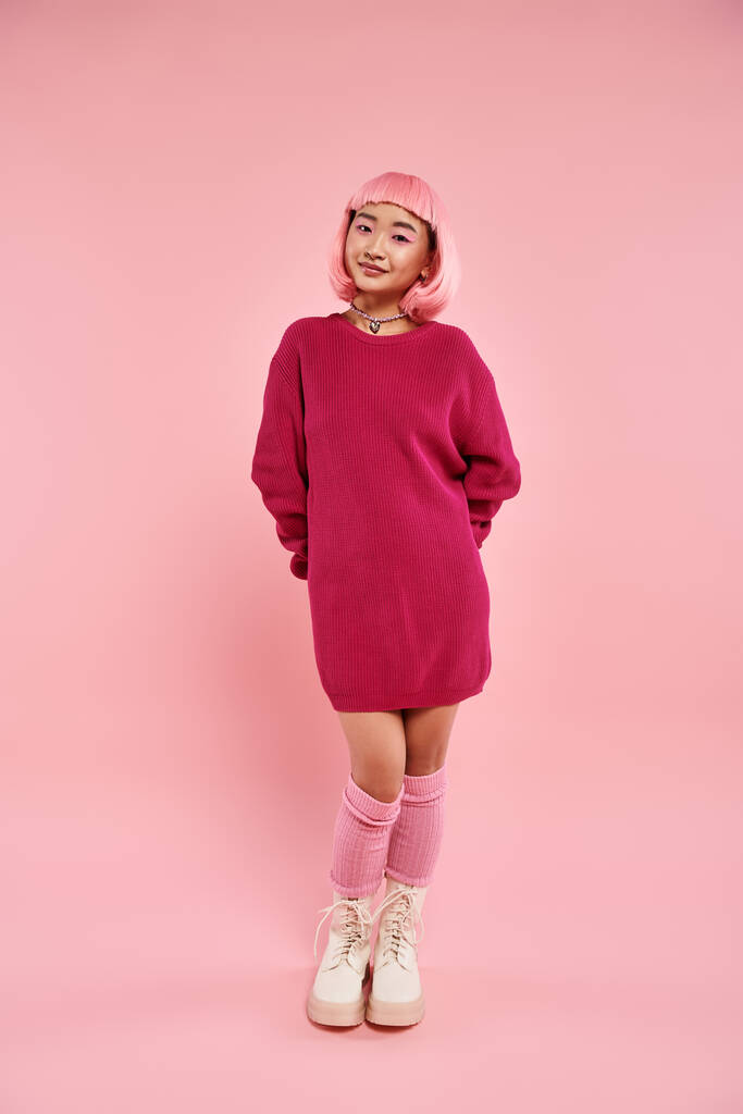 vidám ázsiai nő a 20-as éveiben élénk pulóverben gyöngynyaklánccal rózsaszín háttéren - Fotó, kép