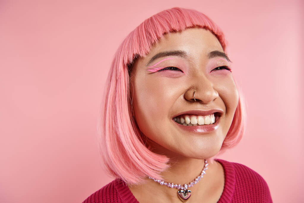 Nahaufnahme einer asiatischen jungen Frau mit Nasenpiercing glücklich lachend auf rosa Hintergrund - Foto, Bild