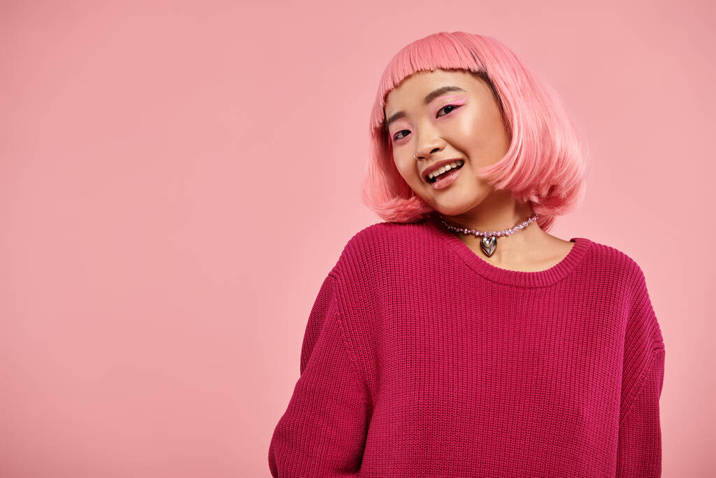 urocza Azjatka młoda kobieta z różowymi włosami patrząc w aparat i uśmiechając się na żywe tło - Zdjęcie, obraz