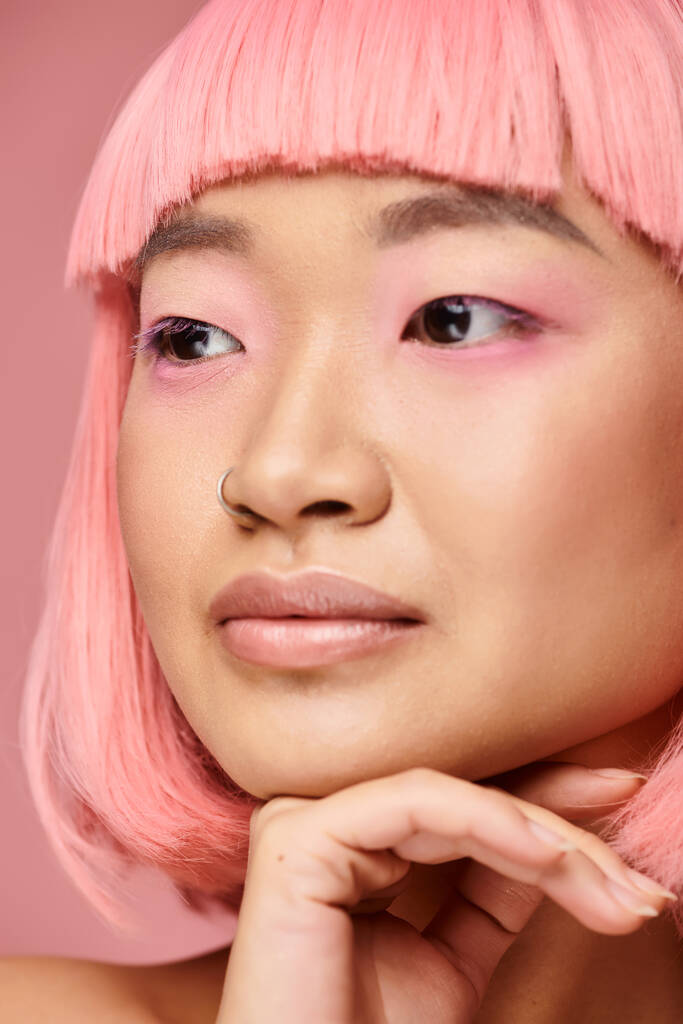 primo piano di seducente ragazza asiatica con i capelli rosa di sostegno al mento con la mano e cercando di lato - Foto, immagini