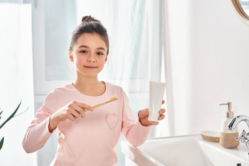 Брюнетка дівчина тримає зубну щітку в сучасній ванній кімнаті, підкреслюючи важливість гігієнічної рутини. - Фото, зображення