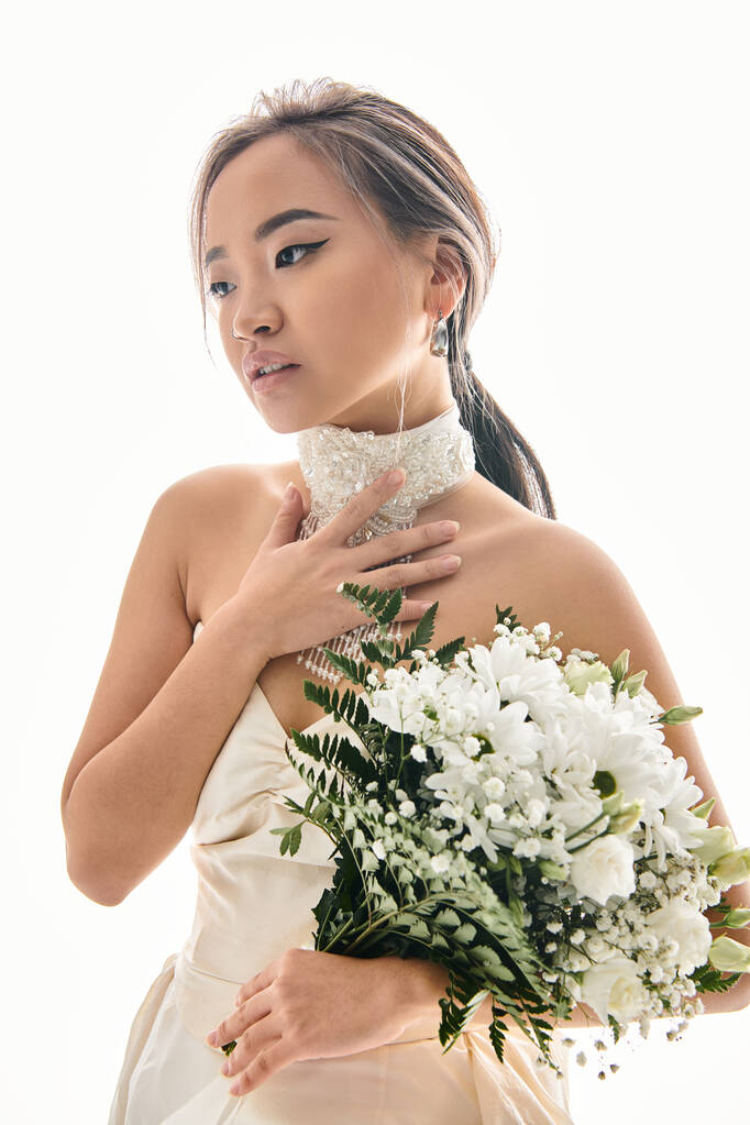 Charmante asiatische Frau berühren, um weiße Halskette und suchen, um Seite mit Blumenstrauß - Foto, Bild