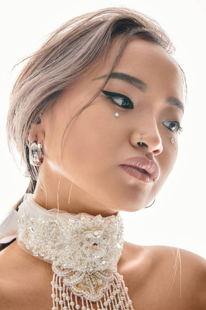 close up de bela mulher asiática com maquiagem elegante inclinando a cabeça para o lado e olhando para baixo - Foto, Imagem