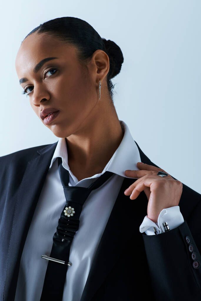 Una giovane donna afroamericana elegante indossa con fiducia un abito e cravatta in un ambiente di studio. - Foto, immagini