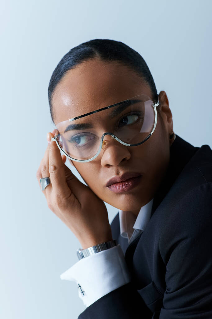 Egy fiatal afro-amerikai nő a húszas éveiben, öltönyben és szemüvegben, pózol egy portréhoz. - Fotó, kép