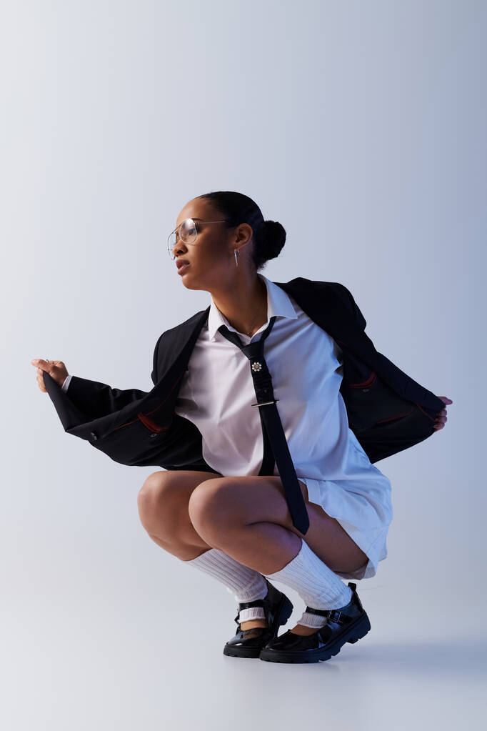 A young African American woman in a suit and tie kneeling down confidently - Photo, Image