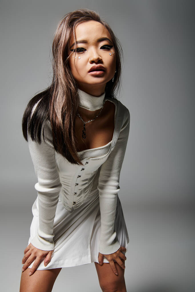 atraente asiático não-padrão noiva com pesado maquiagem inclinado para a frente contra cinza fundo - Foto, Imagem
