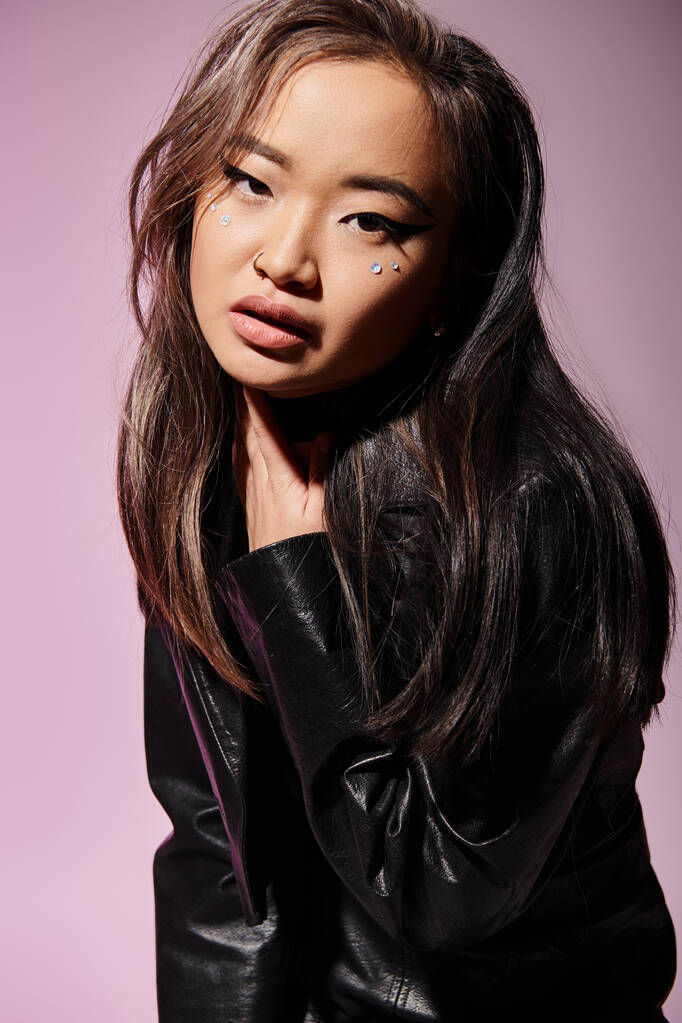 ritratto di bella donna asiatica in pelle nera tenuta al collo con mano su sfondo lilla - Foto, immagini
