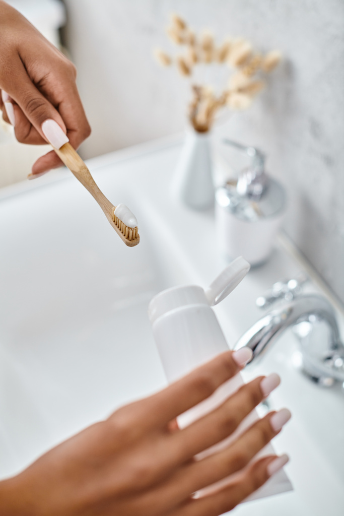 Uma mulher afro-americana de roupão escova os dentes em um banheiro moderno. - Foto, Imagem