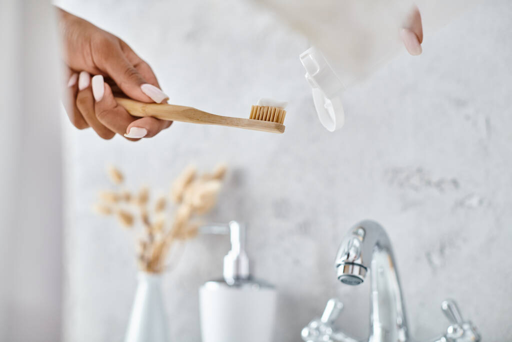 Afroamerykanka w szlafroku trzyma szczoteczkę do zębów w nowoczesnej łazience, podkreślając piękno i rutynę higieny. - Zdjęcie, obraz
