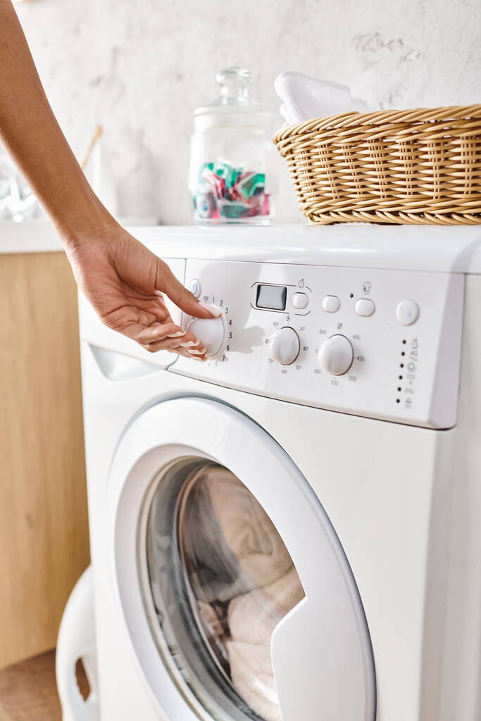 Africká Američanka nastavení tlačítka na pračce při praní v koupelně. - Fotografie, Obrázek