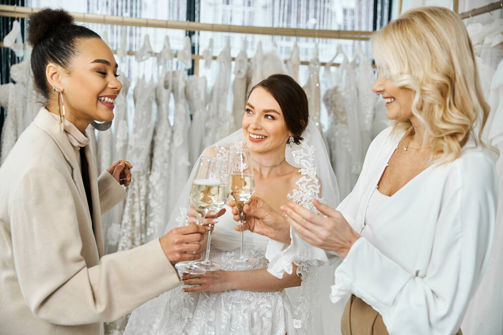 Группа женщин, в том числе молодая невеста, ее мать средних лет, и подружка невесты, стоя вместе и держа бокалы вина. - Фото, изображение