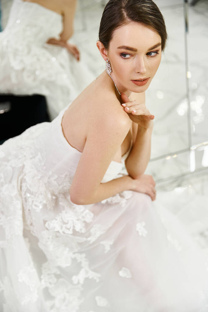 Una joven novia morena exuda elegancia en un vestido blanco mientras posa para una foto en un salón de bodas. - Foto, imagen