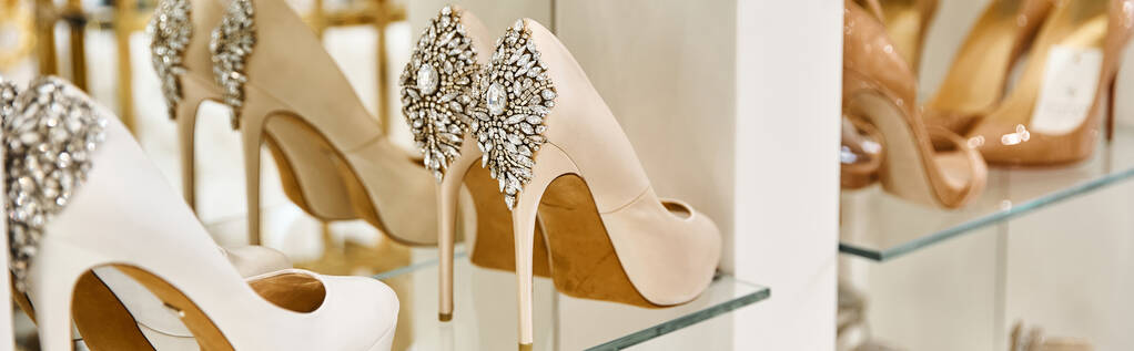 Eine Reihe hochhackiger Schuhe hängt elegant an der Wand und präsentiert eine modische Schuhpräsentation. - Foto, Bild