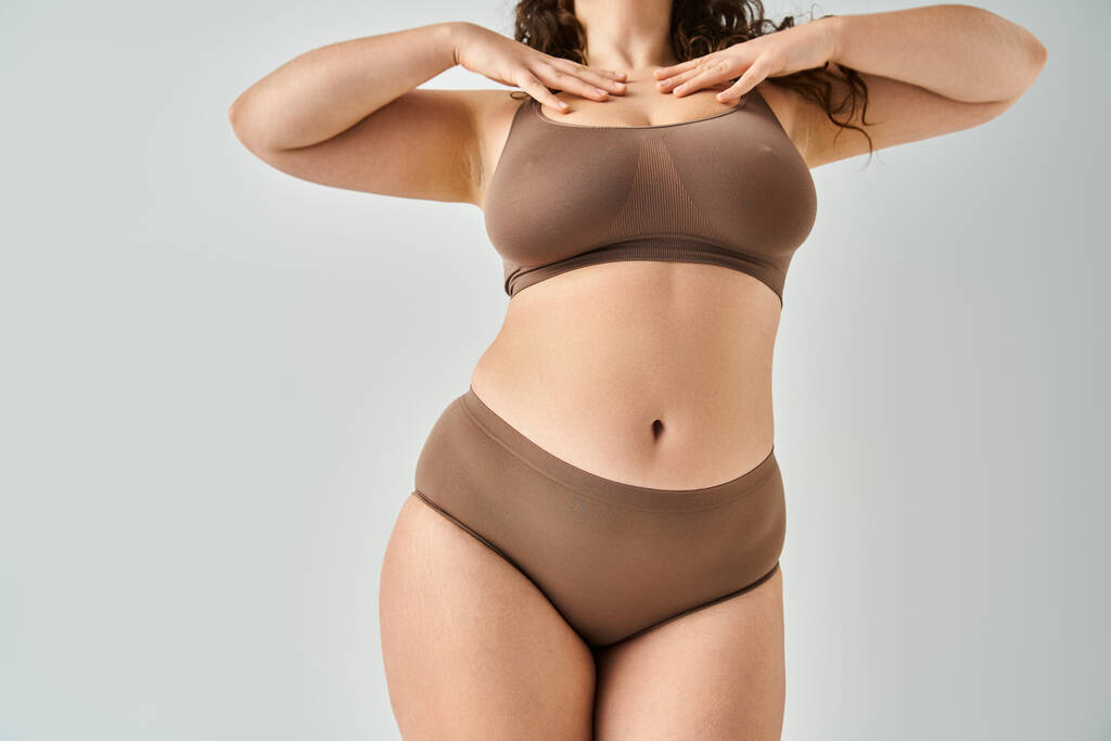 oříznutý záběr těla atraktivní křivky žena ve spodním prádle dotýkající se výstřihu s rukama - Fotografie, Obrázek