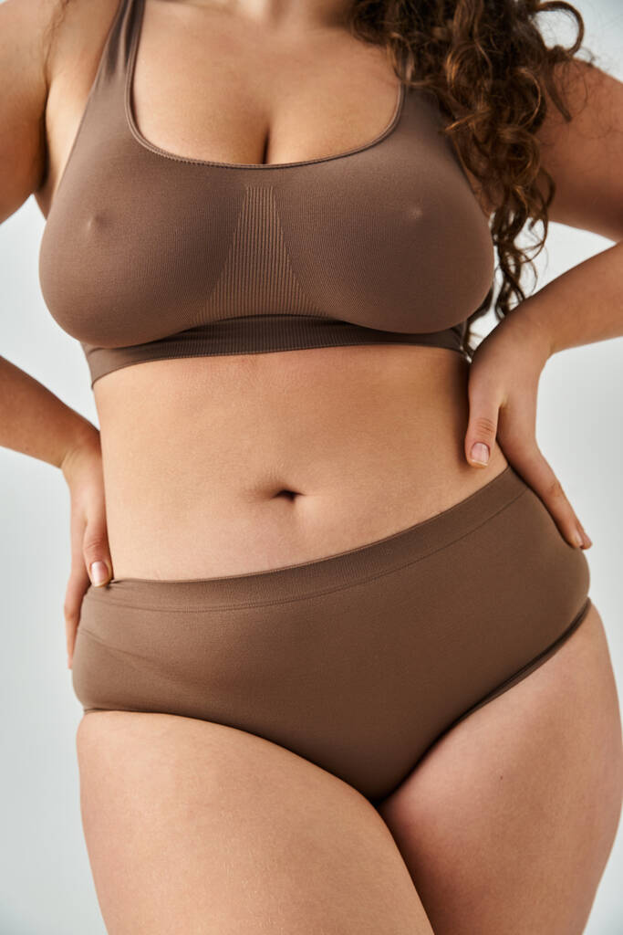 oříznutý záběr těla krásné plus velikost mladá žena ve spodním prádle pózovat proti šedému pozadí - Fotografie, Obrázek