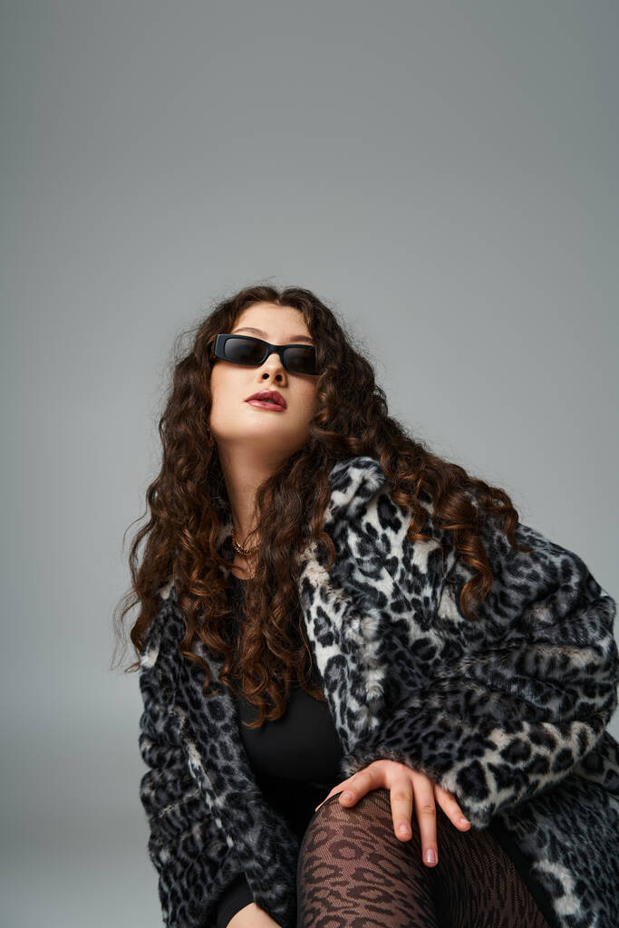 portrait of lovely curvy young woman in leopard fur coat and sunglasses crouching - Photo, Image