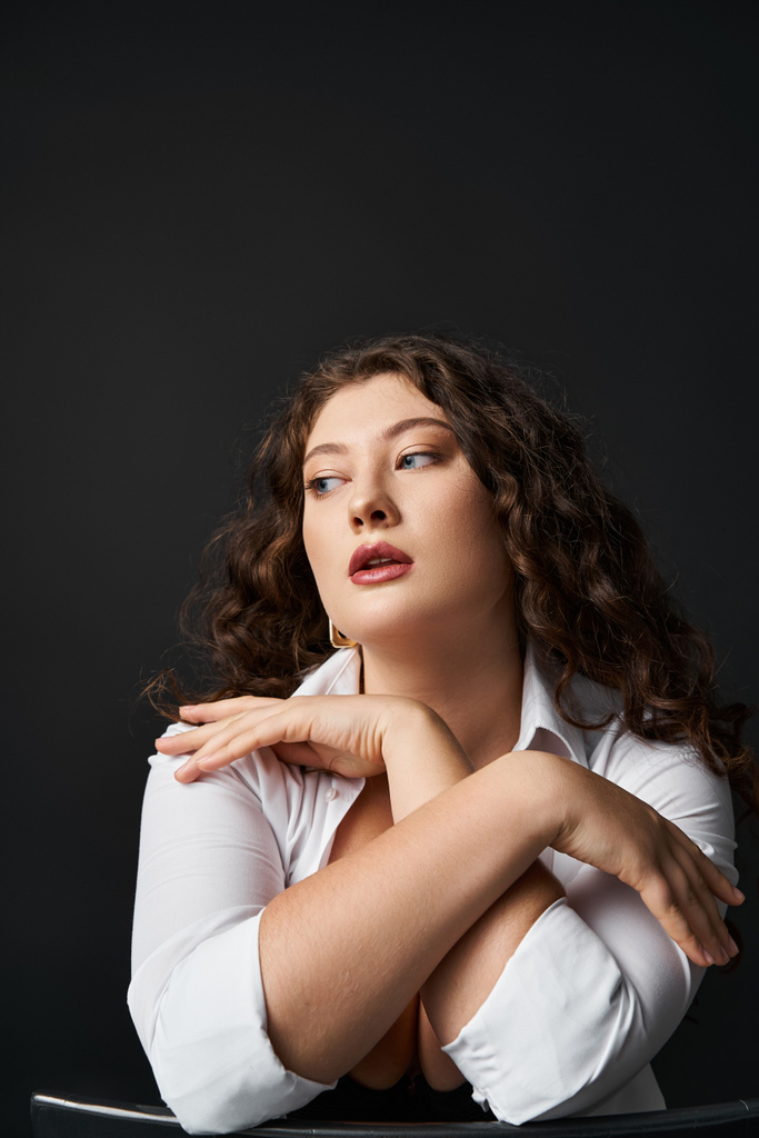 portrait of attractive plus size woman in her 20s hugging neckline and looking to side - Photo, Image