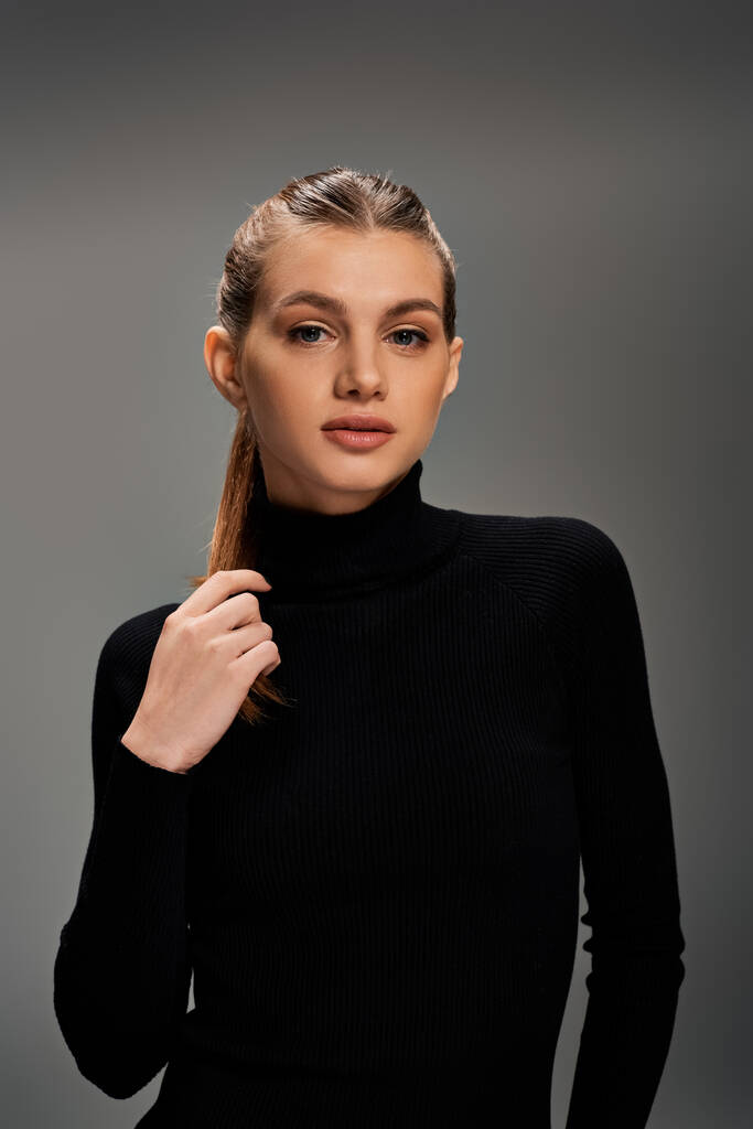 Una mujer joven elegante con el pelo largo con un suéter de cuello alto negro con estilo. - Foto, imagen
