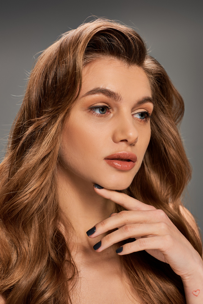 A young woman with long brown hair showcasing her striking black nails in a captivating and mysterious pose. - Photo, Image