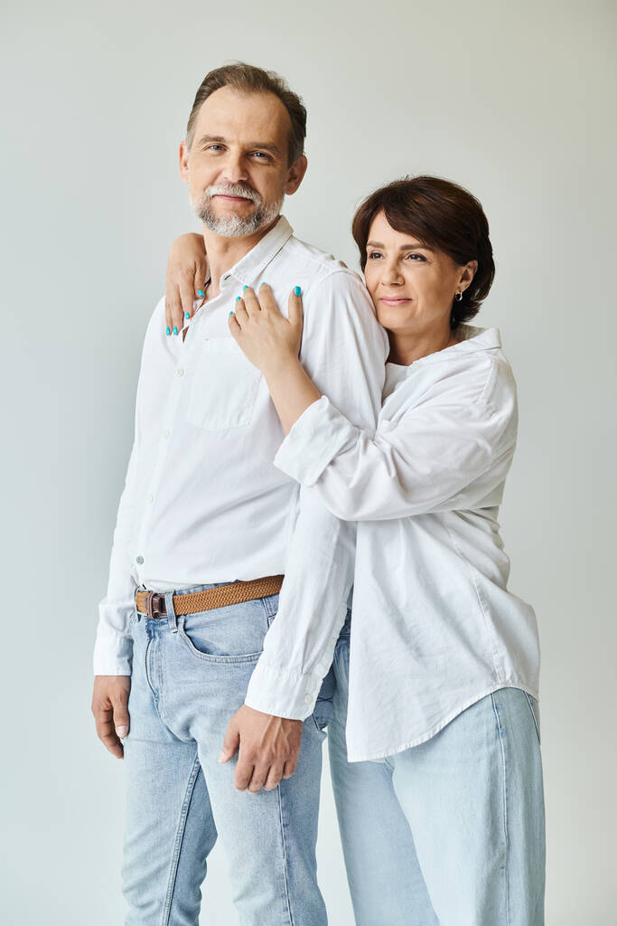 Retrato de pareja elegante hermosa de mediana edad abrazando y sonriendo sobre fondo gris - Foto, imagen